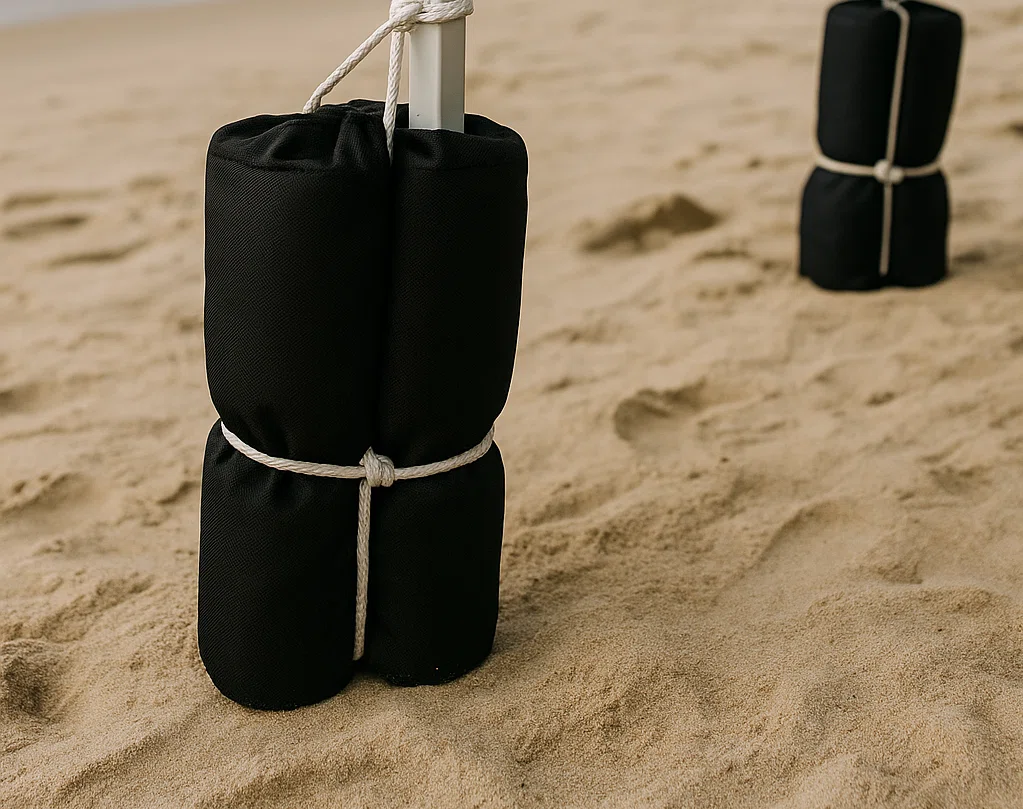 Close-up of sandbags tied to the legs of a canopy tent on a beach.